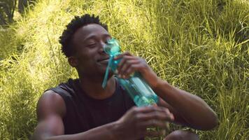 A young African American man engages in a workout routine in a public park, smiling as he enjoys his healthy lifestyle surrounded by nature. The atmosphere is vibrant and invigorating. video