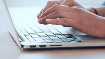 A person types on a sleek laptop keyboard, focused on their work. Natural light streams into the bright room, enhancing a productive atmosphere for writing or researching. video