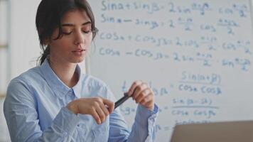 A young woman is conducting an online lesson from her home, engaging students with dynamic content and clear explanations while using her laptop and addressing complex topics. video