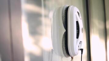 Side view of window cleaning robot on glass with light shadows. video