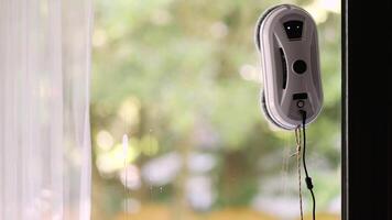 Window cleaning robot on glass with blurred trees background. video