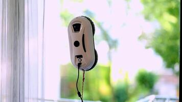 Window cleaning robot on glass with blurred trees background. video