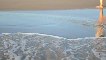 Gentle waves lap at the sandy shore during sunset at the beach, creating a tranquil atmosphere for relaxation and reflection video