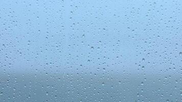 A rainy day view through a window with droplets forming on the glass against a gray sky in the early morning video