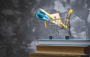 A shopping cart with scissors and books on top of a stack of books photo