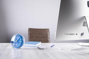 A desk with a computer monitor, a clock, and a mouse photo