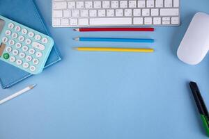 A desk with a keyboard, mouse, pencils, and a calculator photo