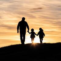 Silhouette of a father and children walking towards the sunset together. photo