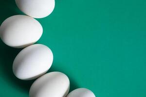 White eggs arranged on a green background with copy space for text photo
