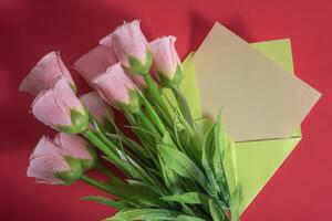 A bouquet of pink flowers and a note on a red background photo