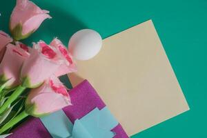 Pink roses and easter egg on green background photo
