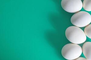 Top view of white eggs on a vibrant green background with copy space photo