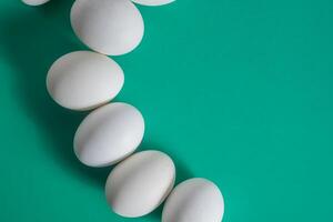 White eggs arranged on a green background with copy space photo