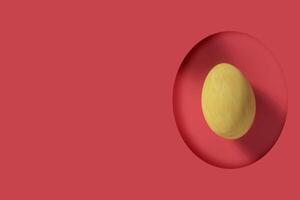 Easter greeting card. Yellow Easter egg visible through egg-shaped gap on red background with copy space. photo