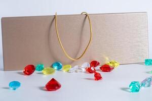 A gold chain on top of an elegant jewelry box surrounded by colorful decorative gems on a white background. photo