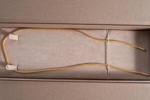 Gold chain elegantly placed in a soft beige jewelry box photo