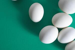 Overhead view of white eggs on a vibrant green background. photo
