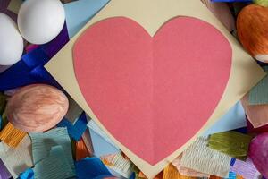 A heart shaped paper is surrounded by colorful eggs photo
