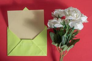 An open green envelope with white roses on a red background photo