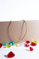 A gold chain on top of an elegant jewelry box surrounded by colorful decorative gems photo