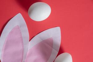A pink background with white eggs and a paper cut out of a bunny photo