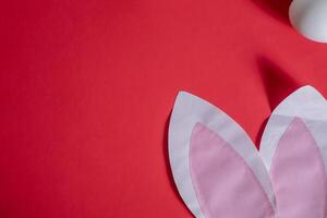 A pink paper bunny ear on a red background photo