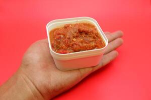 Authentic Lamongan Chili Sauce in a Square White Dish on Red Backdrop photo