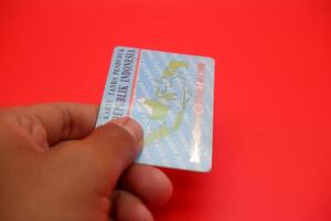 A detailed view of the Indonesian identity card resting on a red surface. The backside of the card is displayed clearly. photo