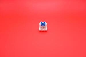 Tactile Blue Keyboard Switch Isolated with Red Backdrop photo