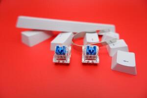 Mechanical Keyboard with Blue Switches, Keycap Puller, and Loose Keycaps on Red photo