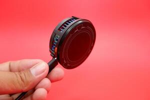 Hand Gripping a Phone Cooler with Cable, Red Background photo
