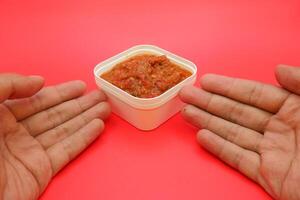 Spicy Lamongan Sambal in a Square White Bowl with a Bold Red Background photo