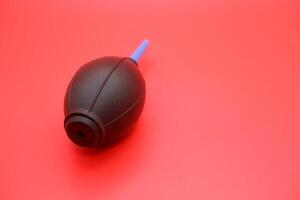 Rubber air blower isolated on a vibrant red background, showcasing its design and details. photo