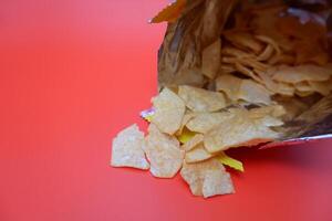 parcialmente inclinado patata papas fritas paquete con meriendas dispersado en rojo foto