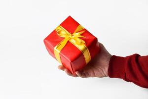 A person hands wearing a red sweater holds and shows a red gift box photo