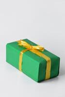 A green gift box with a gold yellow ribbon is on a white isolated background photo
