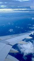 Aerial View from Airplane Wing Over Clouds and Coastline photo