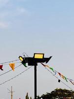 Streetlight with Colorful Flags Against Clear Sky photo