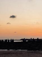 Sunset at Kelan Beach Bali with Airplane Landing and Silhouettes of People Enjoying the Scenic View. Golden Hour Sky, Tranquil Atmosphere, Tropical Destination, Travel, Tourism, Coastal Photography photo