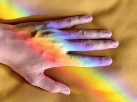 Hand with Rainbow Reflection on Yellow Fabric photo