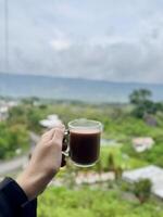 Coffee in Hand with Scenic Greenery Background photo
