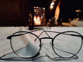 Round Eyeglasses on Table with Candlelight Ambiance. Jimbaran Beach Bali photo