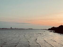 Golden Sunset view and Suramadu Bridge, View from Surabaya to Madura with Harbor and Silhouettes of Ships on the Horizon. A Scenic Twilight Over the Ocean, Dramatic Clouds, Vibrant Sky photo