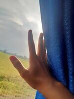 Hand Reaching for Sunlight Through Train Window photo