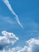 Contrail in a Blue Sky with Fluffy Clouds photo