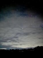 Starry Night Sky with Clouds and Silhouetted Trees. Kawah Wurung Ijen Geopark photo