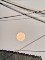 Full Moon Framed by Overhead Wires in an Urban Evening Sky photo