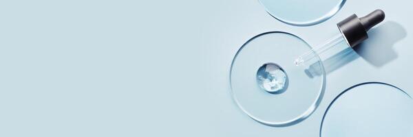 Pipette with sample of gels cosmetic product in petri dish on blue banner, hard shadows photo