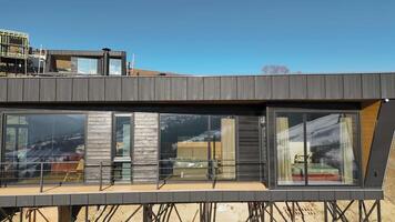 Modern glass house with panoramic mountain views, contemporary architecture blending with nature, large windows reflecting snowy landscapes video