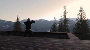 Man meditating in the mountains, peaceful winter scenery with trees and snowy peaks video